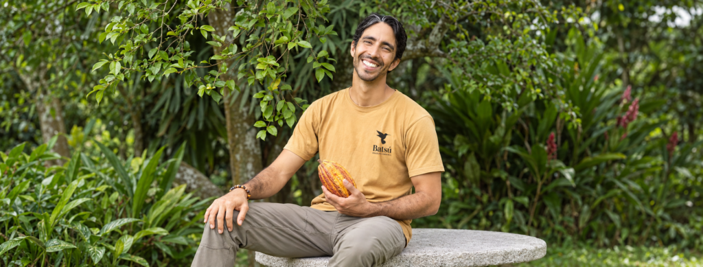 Julián sosteniendo una mazorca de cacao con camiseta de Batsú